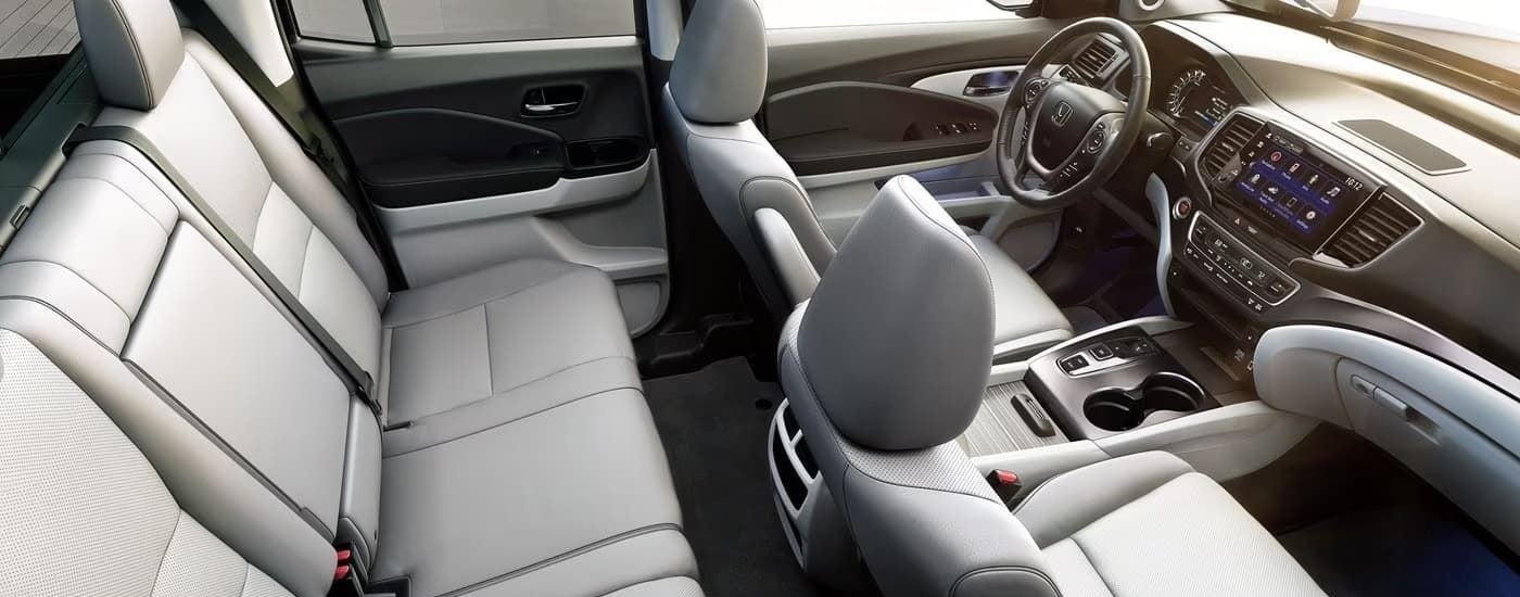 The grey interior of a 2022 Honda Ridgeline shows two rows of seating and the dashboard.