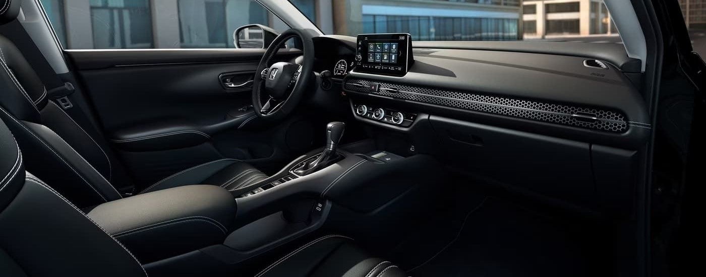 The black interior of a 2023 Honda HR-V shows the steering wheel and center console.