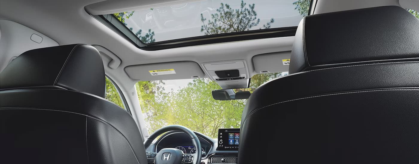 A view from the backseat of a 2024 Honda Civic Touring shows the front seating and sunroof.