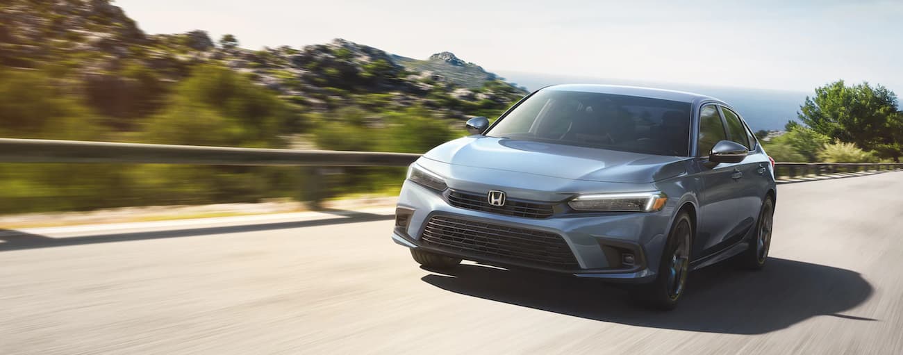 A grey 2022 Honda Civic for sale is shown driving on an open road.