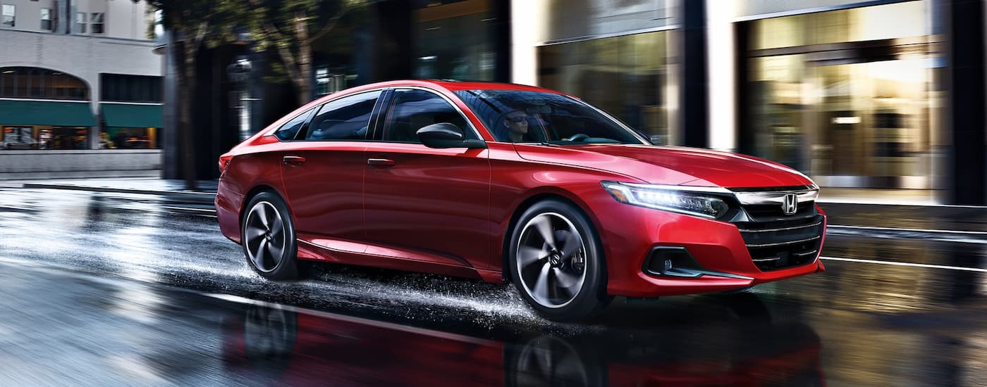 A red 2022 Honda Accord Sport is shown driving on a city street.