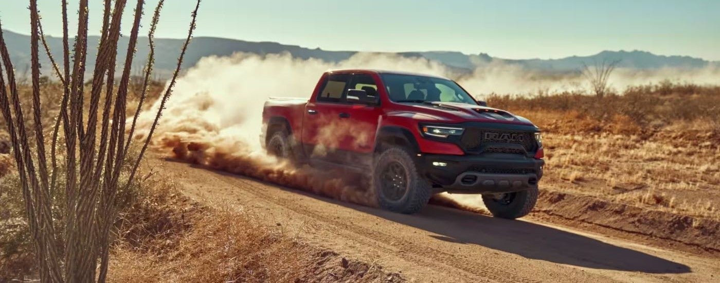 A red 2022 Ram 1500 TRX is shown kicking up dust.
