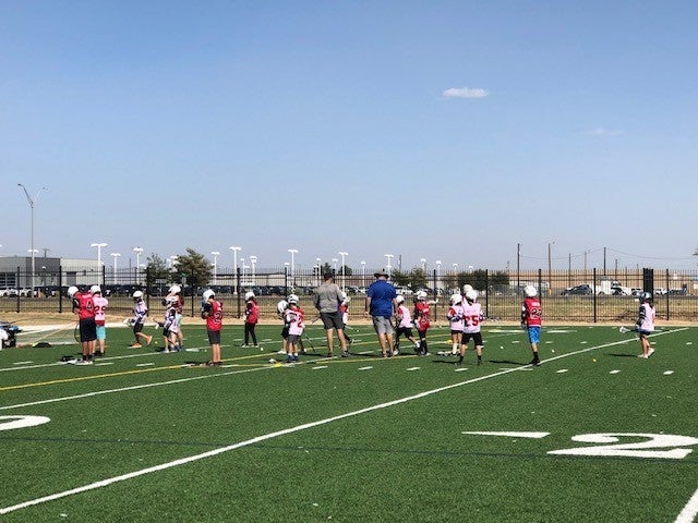 Texas Lacrosse Team Practicing in a Green Field with Coaches