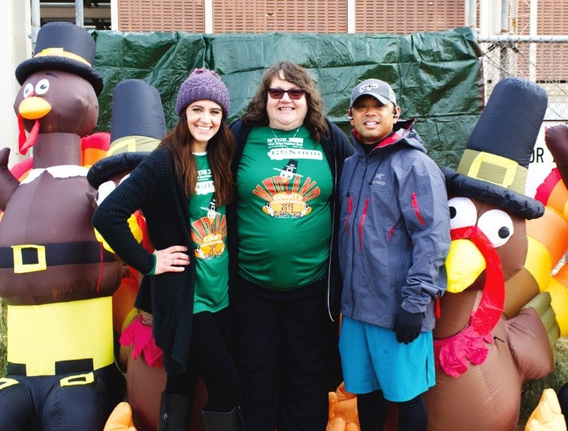 Two Women and a Man Standing in Front of Blow Up Turkeys Outside